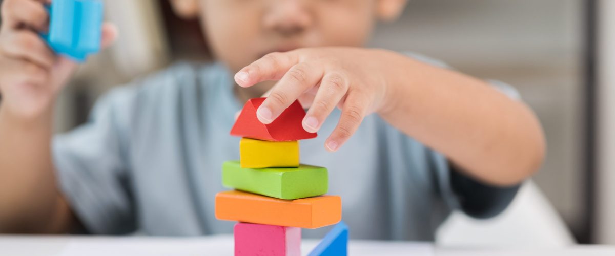 Close up Children hand Practice the skills of playing with wooden toys on the table in living room. Asian little boy education from home. Developing children's learning before entering kindergarten